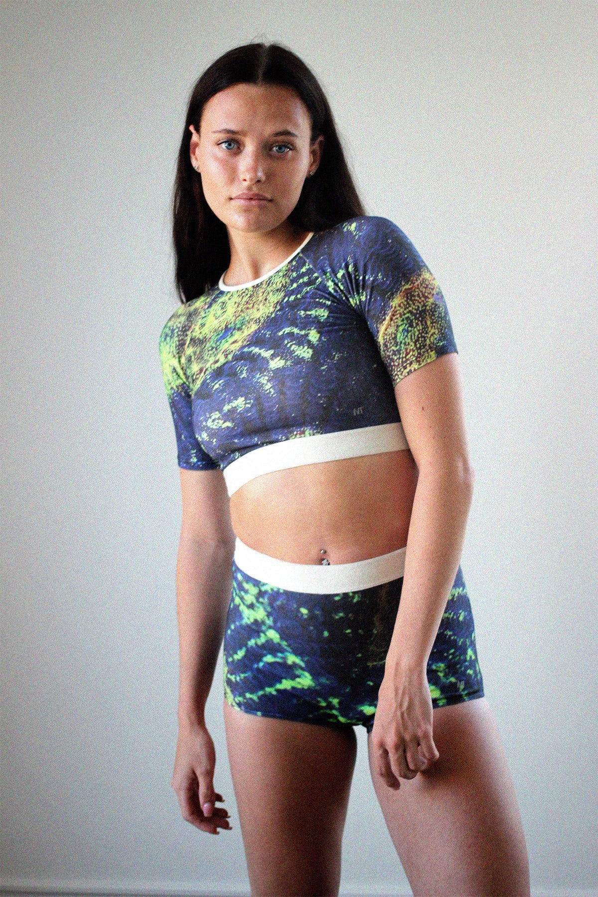girl women wearing rash-guard printed in coral image in blue and neon green print made out of plant based fabric and hemp. girl with blue eyes and brown hair.